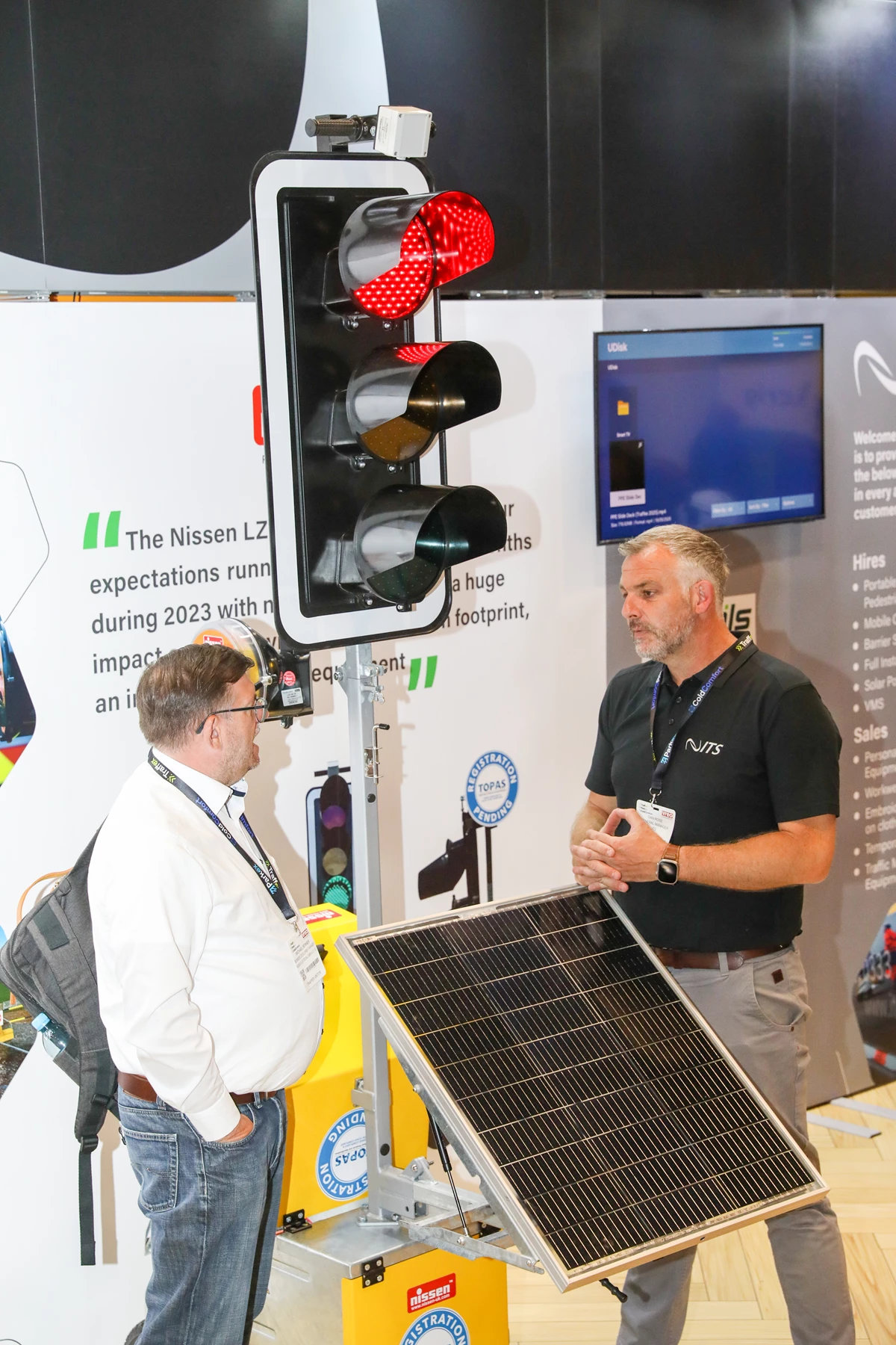 An exhibitor demonstrating traffic signal equipment to a visitor at Traffex